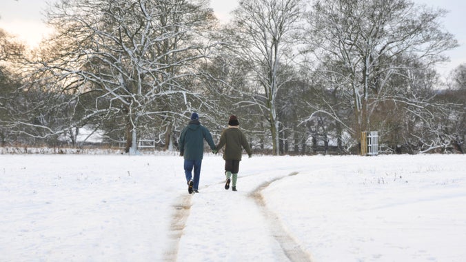 Visitors enjoy a winter walk across snow-covered grounds, following a path through the landscape framed by frost-covered trees.